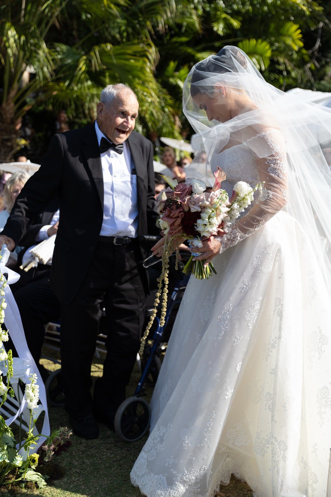 The bride walking the aisle with her grandfather, veil over her face, Airlie Beach