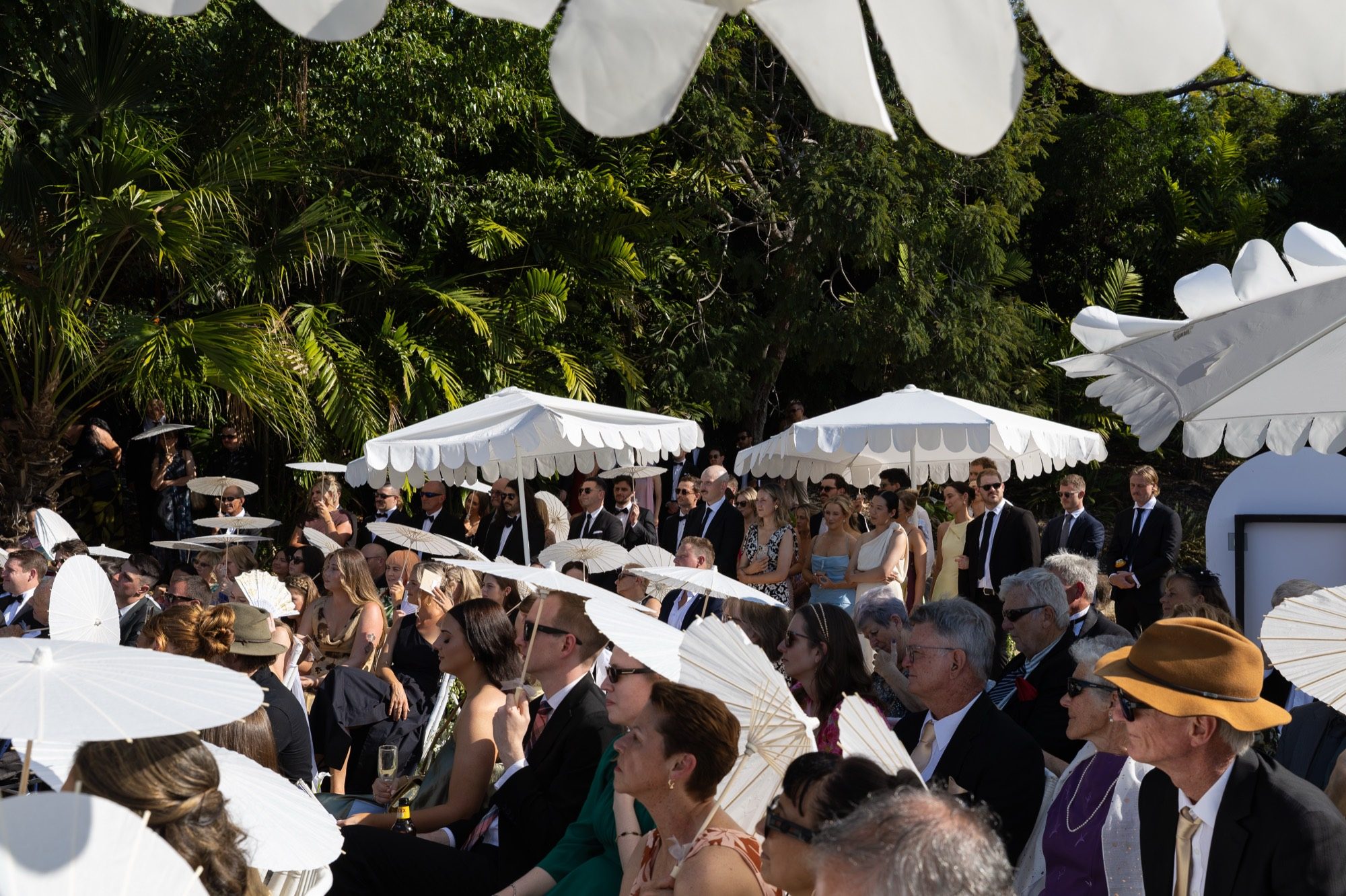 Guests under white parasols and scalloped umbrellas during the tropical ceremony, Freedom Shores, Airlie Beach