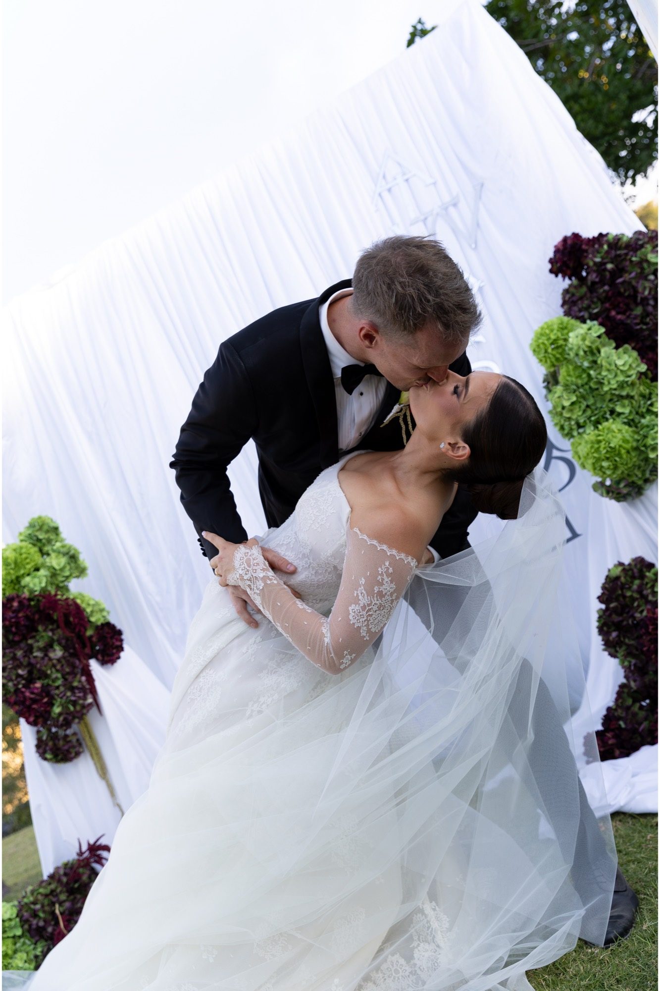 The groom dipping the bride into a kiss before the monogram backdrop, Freedom Shores, Airlie Beach